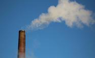 Factory tower releasing smoke into a blue sky